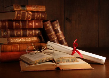 Pile of old books with glasses on desk